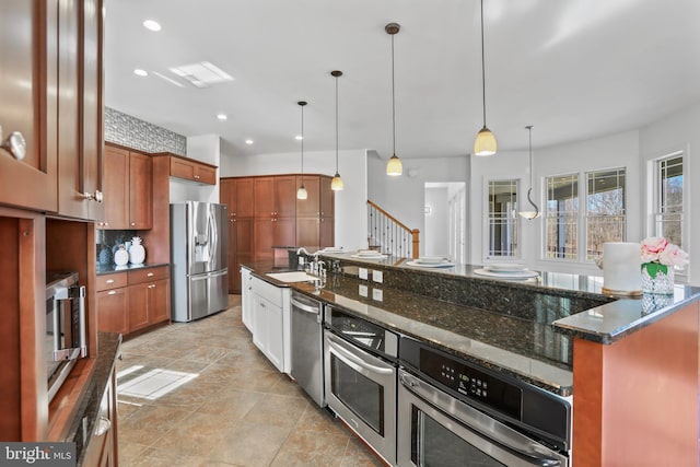 kitchen featuring stainless steel appliances, light tile floors, decorative light fixtures, dark stone counters, and sink