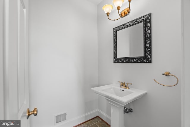 bathroom featuring an inviting chandelier and tile flooring