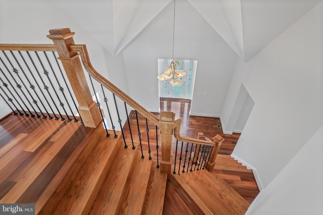 stairway featuring a high ceiling, a chandelier, and dark wood-type flooring