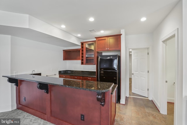 kitchen featuring light tile floors, dark stone countertops, a kitchen breakfast bar, and kitchen peninsula