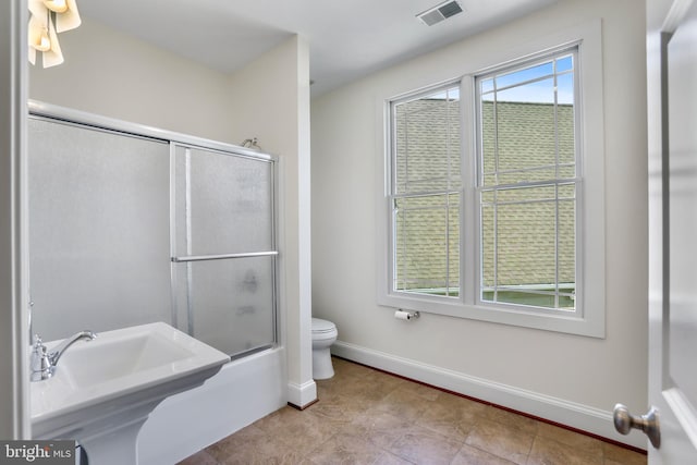 full bathroom with toilet, tile flooring, sink, and bath / shower combo with glass door