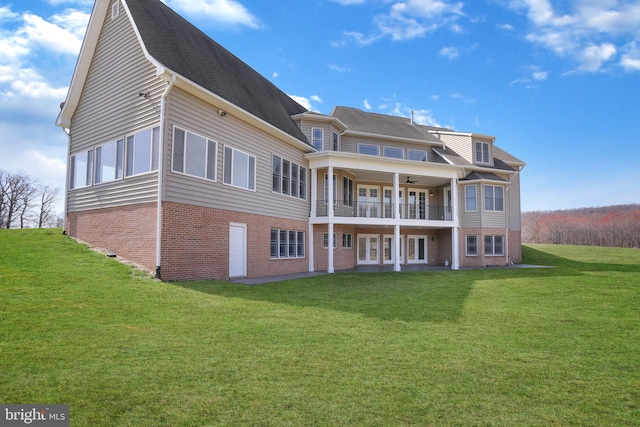 back of property featuring a balcony and a lawn