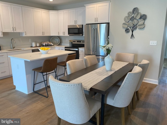 kitchen featuring white cabinets, a kitchen breakfast bar, sink, a kitchen island, and stainless steel appliances