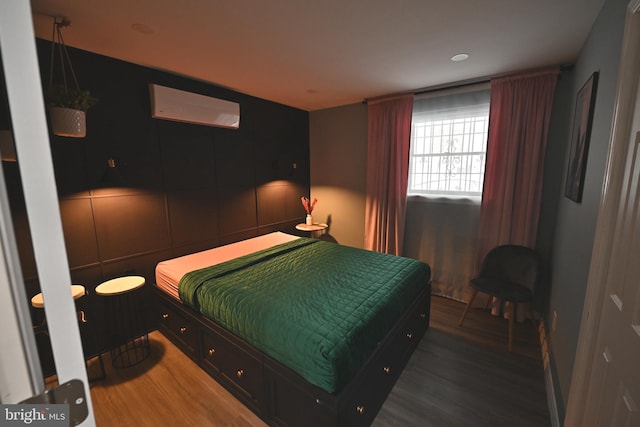 bedroom featuring dark wood-type flooring and a wall unit AC