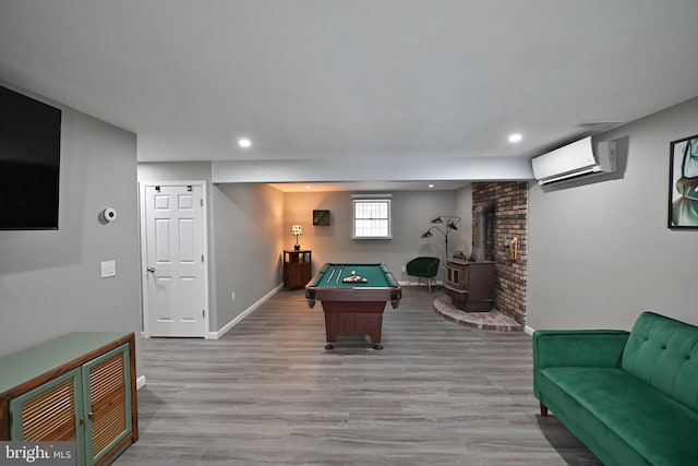 rec room featuring billiards, a wood stove, an AC wall unit, and wood-type flooring