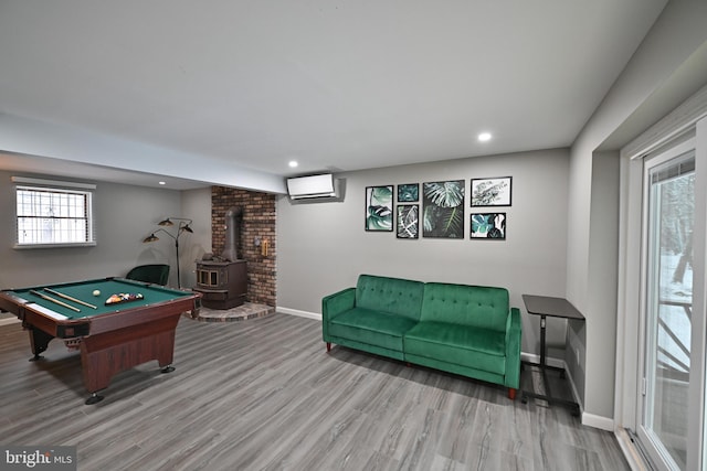 recreation room featuring a wood stove, pool table, a wall unit AC, and wood-type flooring