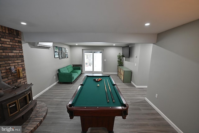 recreation room with dark wood-type flooring, a wood stove, an AC wall unit, and pool table