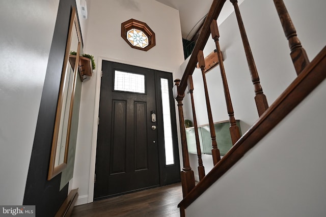 entryway with a baseboard heating unit, dark hardwood / wood-style floors, and a towering ceiling