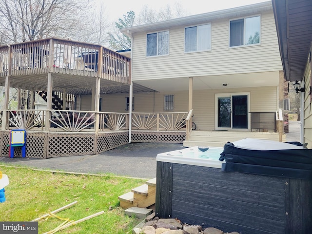 rear view of house featuring a deck and a hot tub