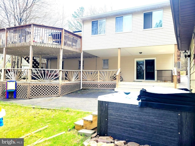 back of house featuring a hot tub, a yard, and a deck