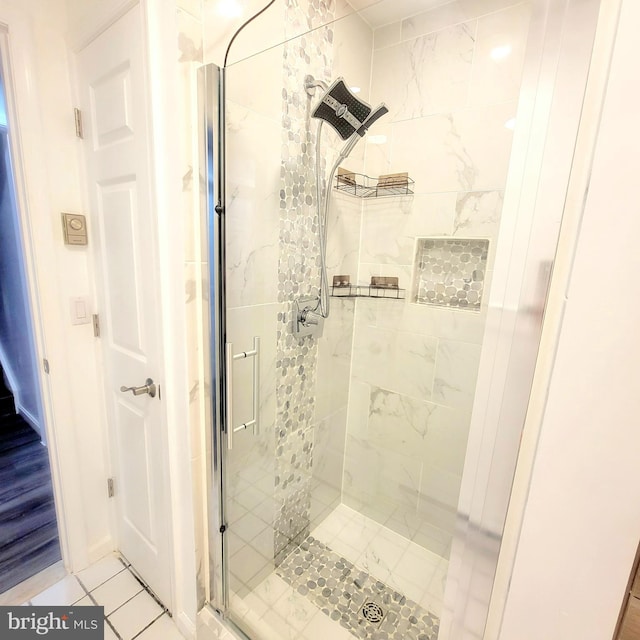 bathroom with a shower with door and tile patterned floors