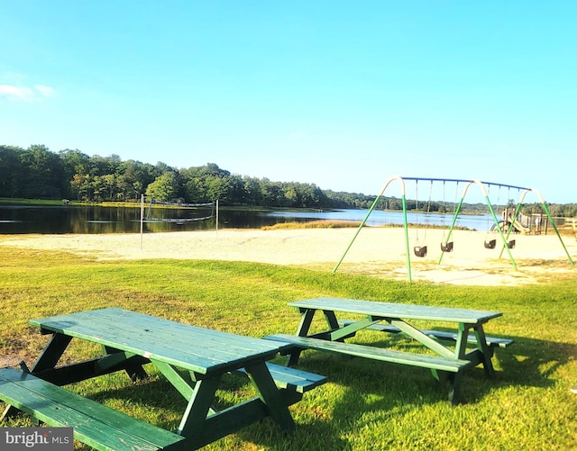 view of home's community with a water view, a lawn, and a playground