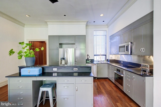 kitchen with backsplash, dark wood-type flooring, stainless steel appliances, gray cabinets, and ornamental molding