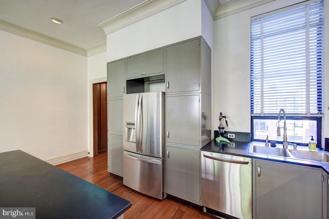 kitchen with dark hardwood / wood-style floors, ornamental molding, appliances with stainless steel finishes, and sink