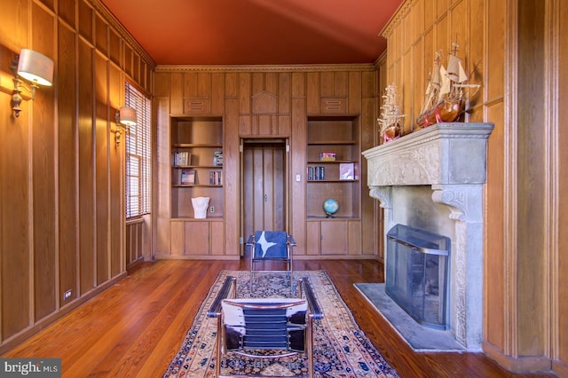 interior space featuring built in shelves, wood walls, dark hardwood / wood-style floors, and crown molding