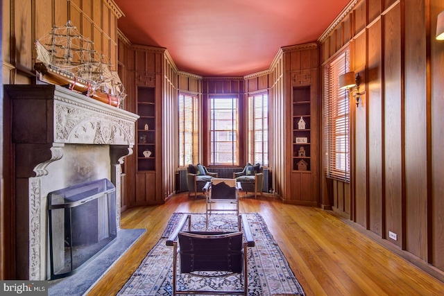 living area with built in shelves, a high end fireplace, and light wood-type flooring