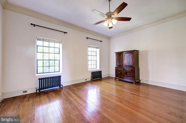 empty room with ceiling fan, crown molding, light hardwood / wood-style floors, and radiator heating unit