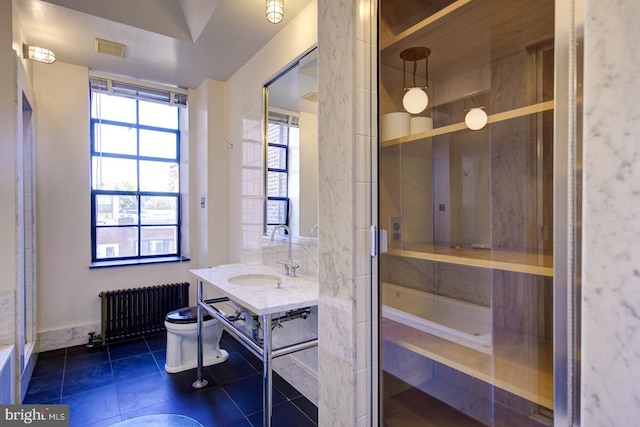 bathroom featuring tile floors, toilet, radiator, a bathtub, and oversized vanity