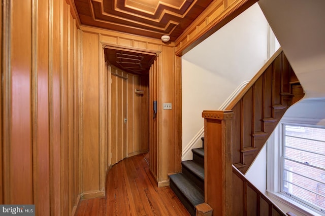 staircase featuring wooden ceiling, ornamental molding, and light hardwood / wood-style floors