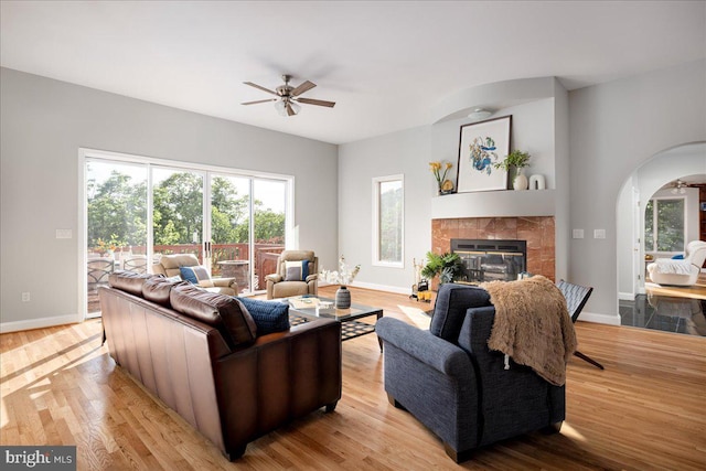 living room with light hardwood / wood-style floors, a tile fireplace, and ceiling fan