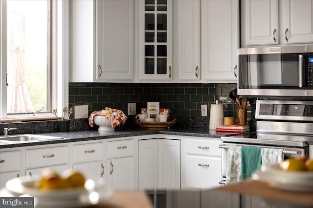kitchen with stainless steel appliances, white cabinets, and backsplash