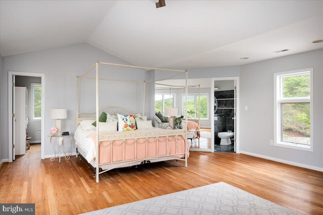 bedroom with hardwood / wood-style floors, ensuite bathroom, lofted ceiling, and multiple windows