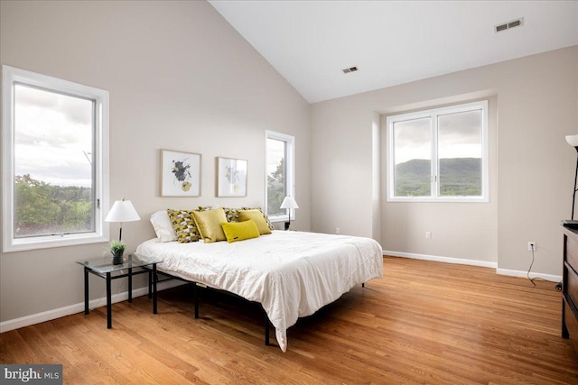 bedroom featuring high vaulted ceiling and light wood-type flooring