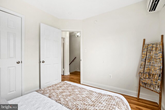 bedroom with hardwood / wood-style floors and an AC wall unit