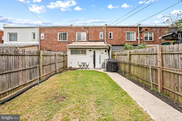 rear view of property featuring a lawn and a patio area