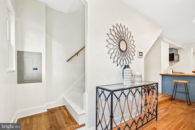 staircase with electric panel and hardwood / wood-style floors