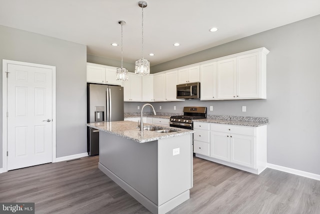 kitchen with white cabinets, a kitchen island with sink, stainless steel appliances, light wood-type flooring, and sink