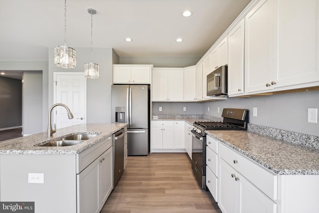 kitchen featuring stainless steel appliances, white cabinets, sink, and a kitchen island with sink