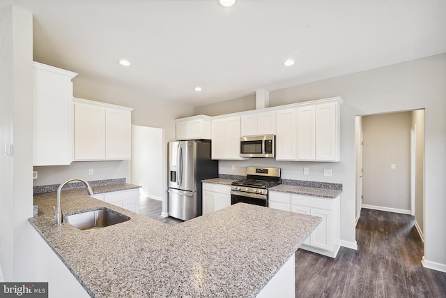 kitchen featuring kitchen peninsula, dark wood-type flooring, stainless steel appliances, white cabinetry, and sink