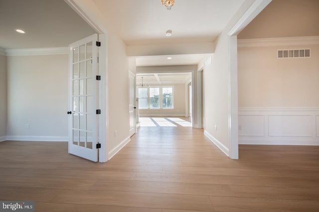 corridor with french doors, crown molding, and light wood-type flooring