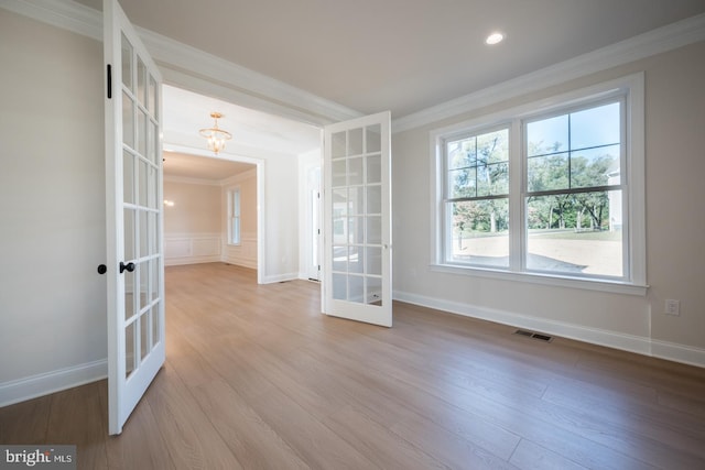 empty room with ornamental molding, french doors, and light wood-type flooring