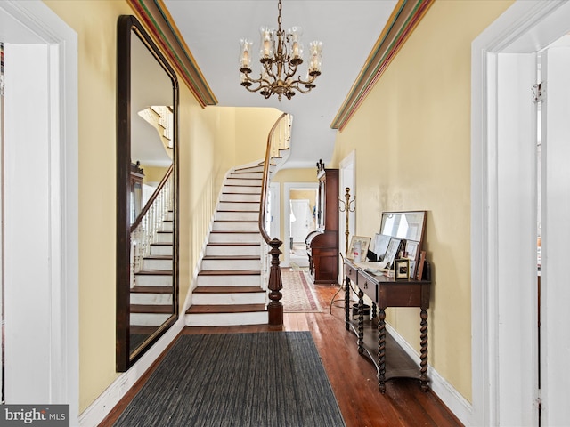 foyer entrance featuring a notable chandelier, crown molding, and dark wood-type flooring