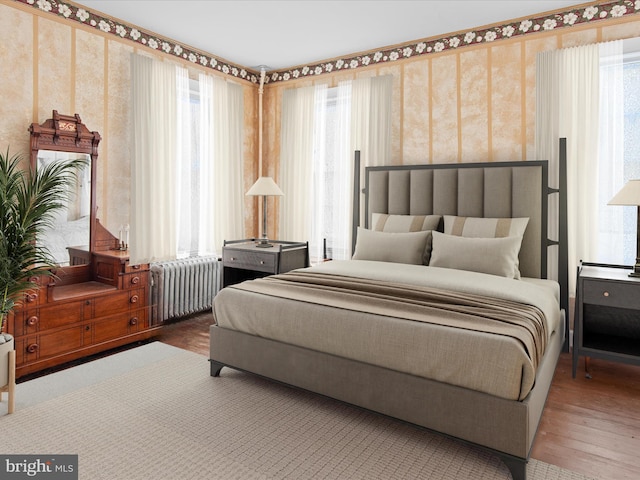 bedroom with radiator heating unit, hardwood / wood-style flooring, and multiple windows