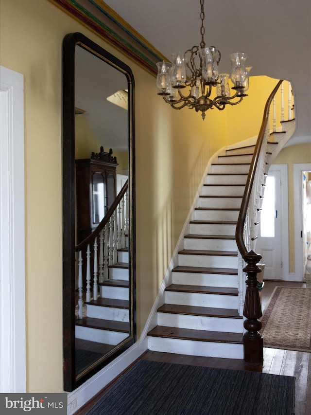 stairs with an inviting chandelier, dark hardwood / wood-style floors, and ornamental molding