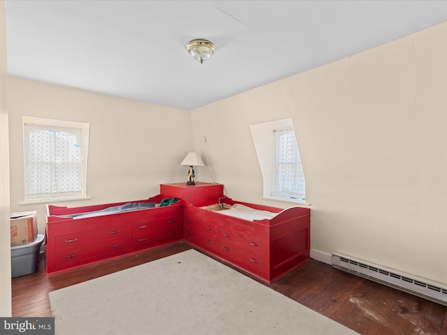 bedroom with dark hardwood / wood-style floors and a baseboard heating unit