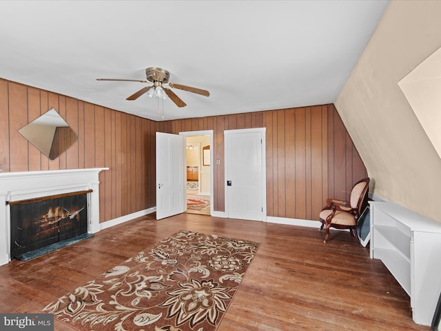 sitting room with dark hardwood / wood-style flooring, ceiling fan, and wooden walls