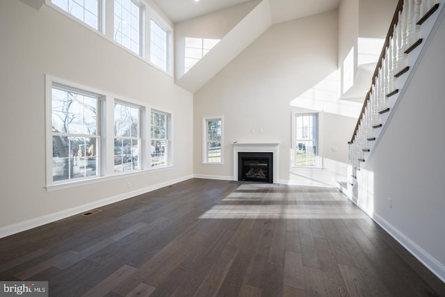 unfurnished living room featuring high vaulted ceiling and dark hardwood / wood-style flooring