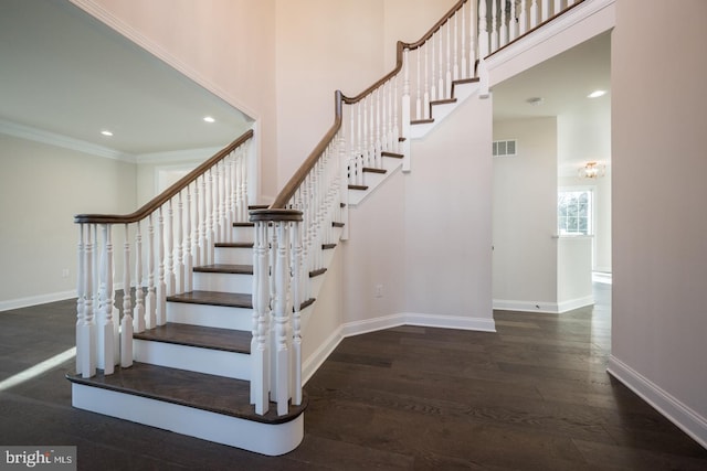 stairway featuring a high ceiling, dark hardwood / wood-style flooring, and ornamental molding