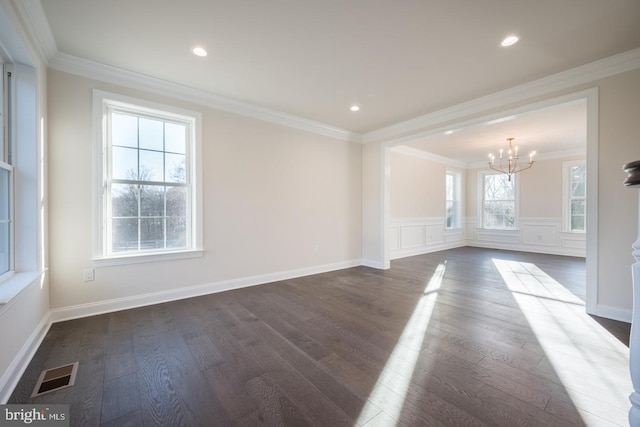 spare room featuring a notable chandelier, ornamental molding, and dark wood-type flooring