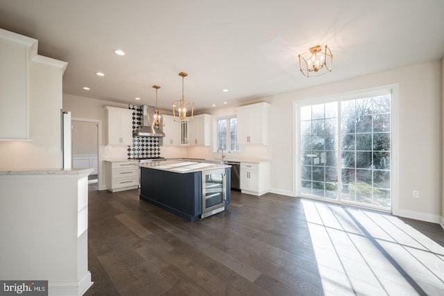 kitchen with wall chimney range hood, dark hardwood / wood-style floors, white cabinets, and a center island