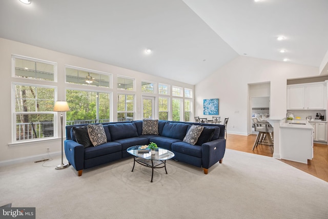 carpeted living room with plenty of natural light, high vaulted ceiling, and sink