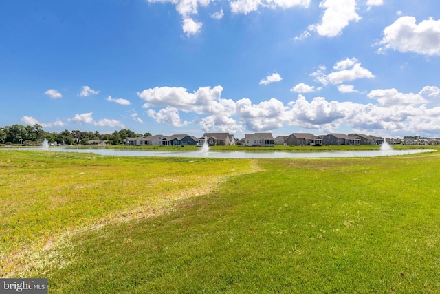 surrounding community with a water view and a yard