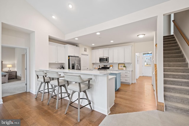 kitchen featuring a breakfast bar, light hardwood / wood-style floors, appliances with stainless steel finishes, and white cabinetry