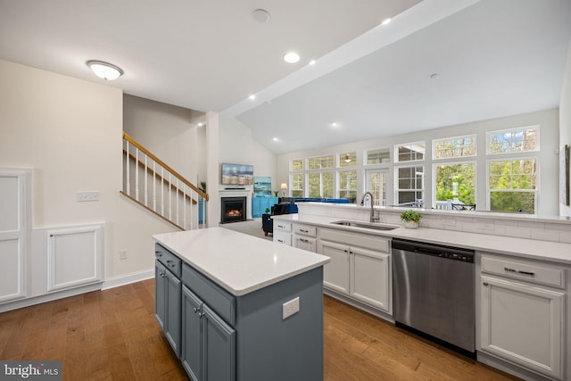 kitchen with hardwood / wood-style flooring, stainless steel dishwasher, gray cabinetry, lofted ceiling, and sink