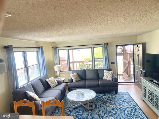 living room with plenty of natural light, a textured ceiling, and light wood-type flooring