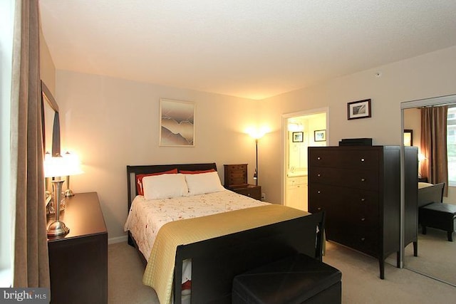 bedroom with light colored carpet and ensuite bath